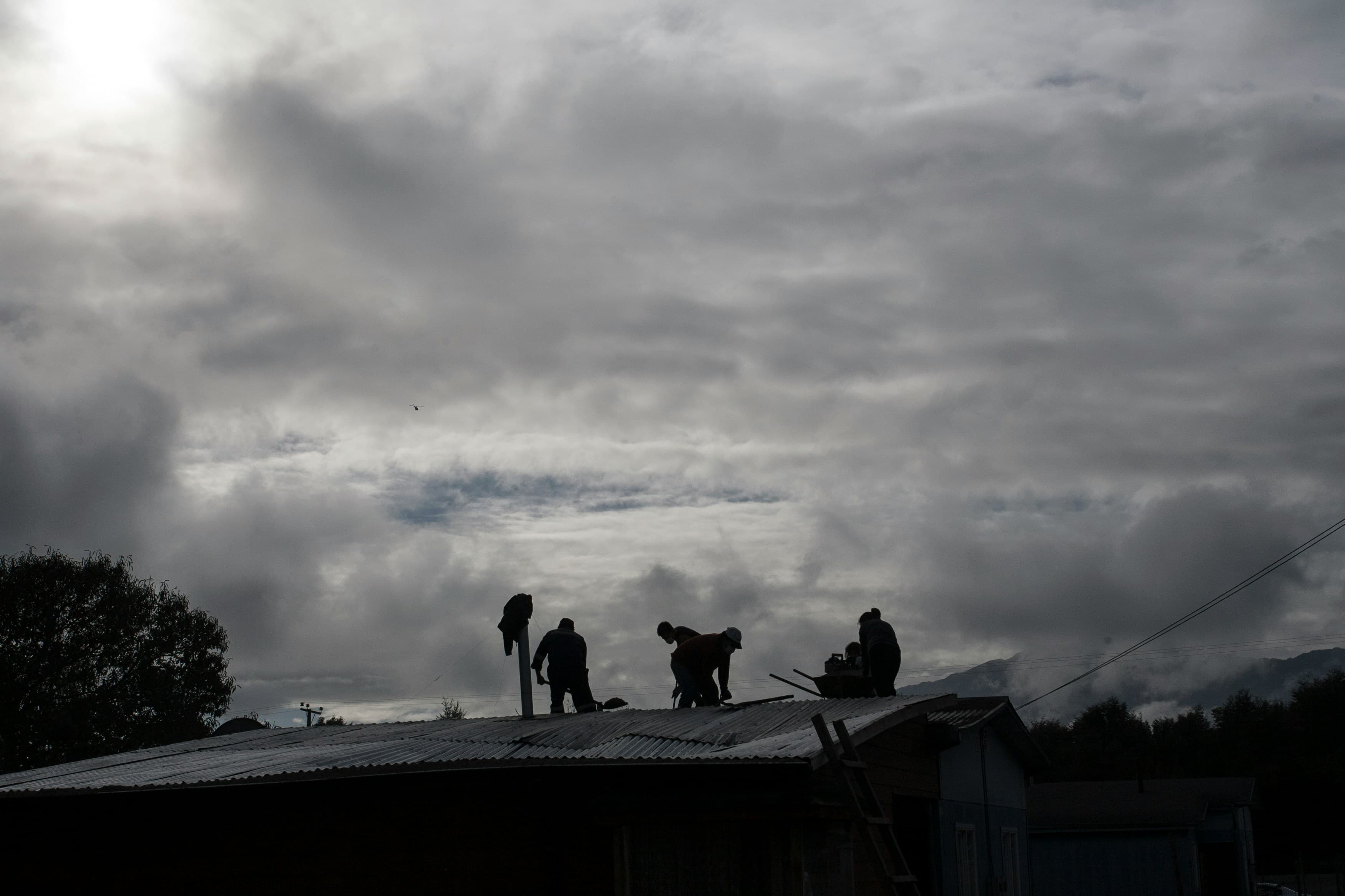 Roofing crew working under dark storm clouds